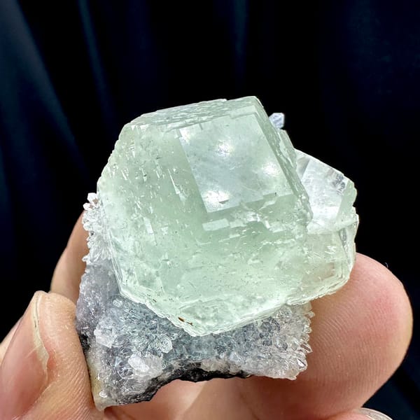 Large glass-clear pale green fluorite cube on lavender druse from Fujian, China, close-up of the crystal faces