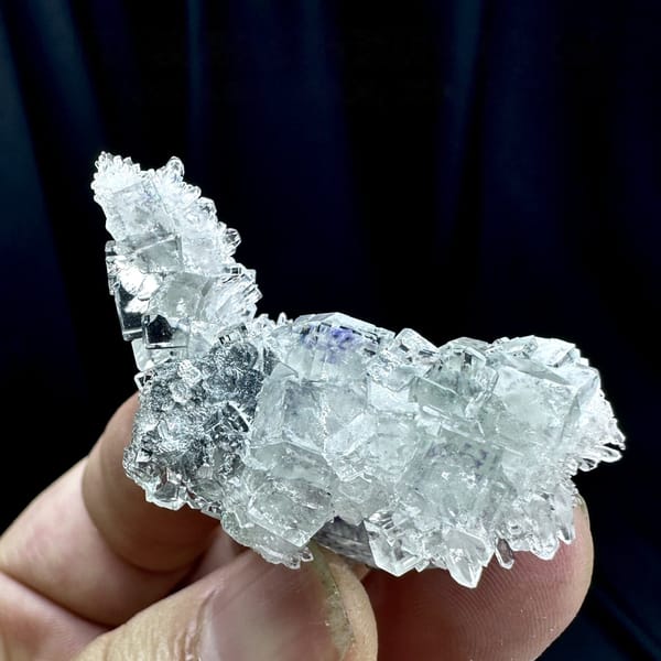 Glass-clear fluorite cubes with faint blue tint on quartz from Zhejiang, China, detail of the matrix contact