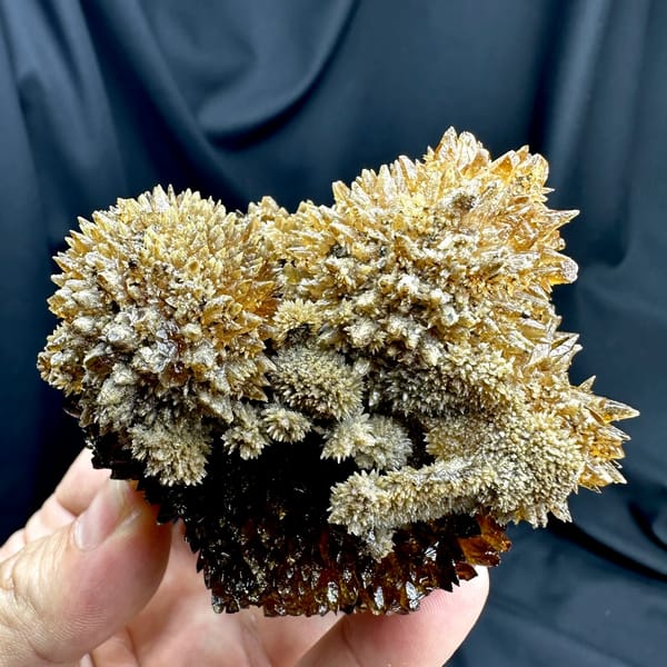 Amber calcite spires with hyalite opal from Guizhou, China, front view in daylight, held in hand