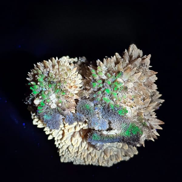 Amber calcite spires with hyalite opal under UV light from Guizhou, China, held in hand