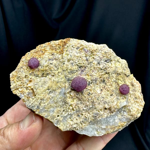 Three raspberry-pink fluorite balls on pale sandstone from Henan, China, top view
