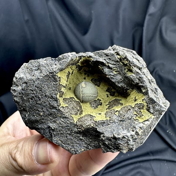 Matcha-green calcite ball inside yellow-lined rock pocket from Fujian, China, detail of the matrix contact