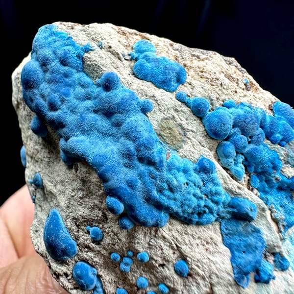 Bright blue chrysocolla balls on grey rock from DR Congo, close-up of the crystal faces