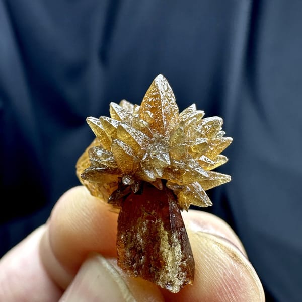 Single amber calcite flower of radiating crystals from Guizhou, China, detail of the matrix contact
