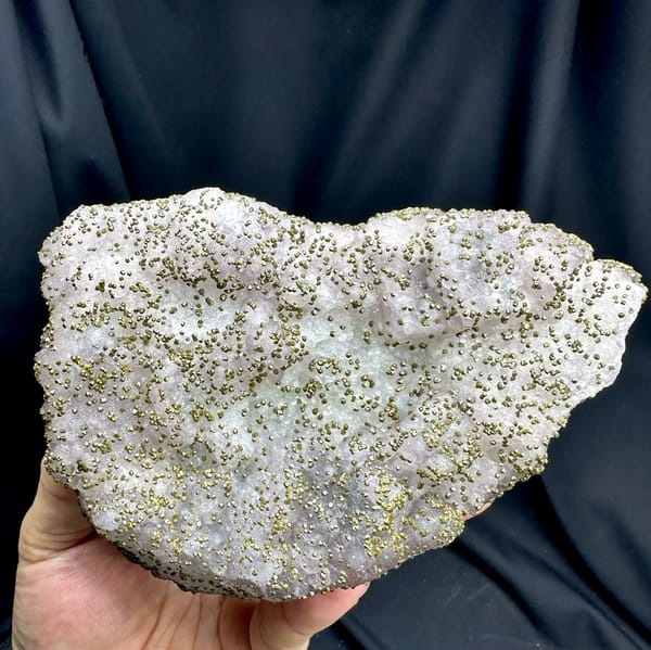 Large lavender-green fluorite floater dusted with pyrite from Jiangxi, China, held in hand