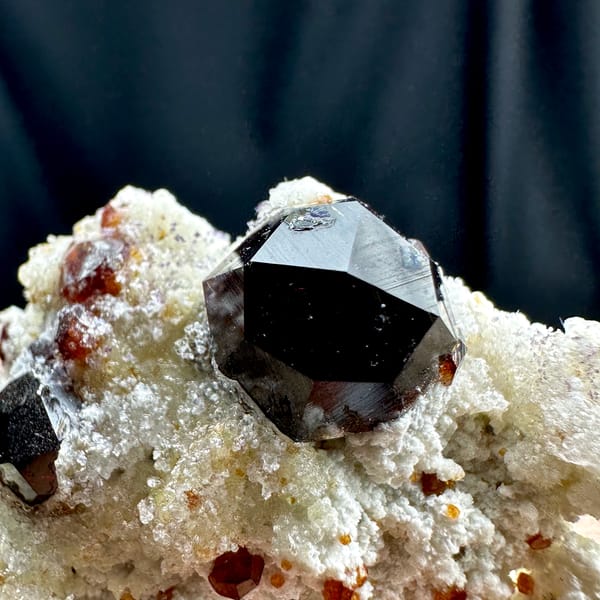 Large wine-red garnets with hyalite opal on white feldspar from Yunxiao, Fujian, China, close-up of the crystal faces