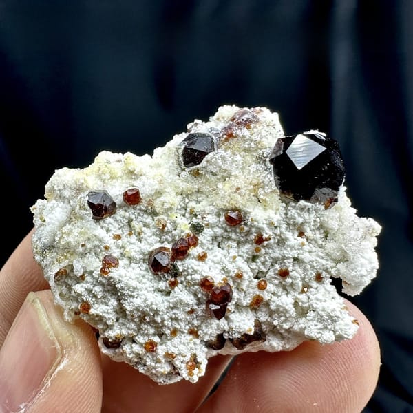 Large wine-red garnets with hyalite opal on white feldspar from Yunxiao, Fujian, China, detail of the matrix contact