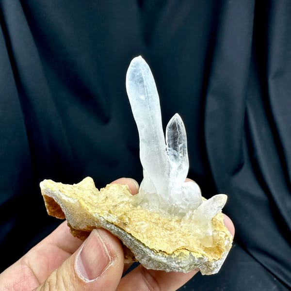 Transparent icicle calcite stalactites on tan base from Yunnan, China, close-up of the crystal faces