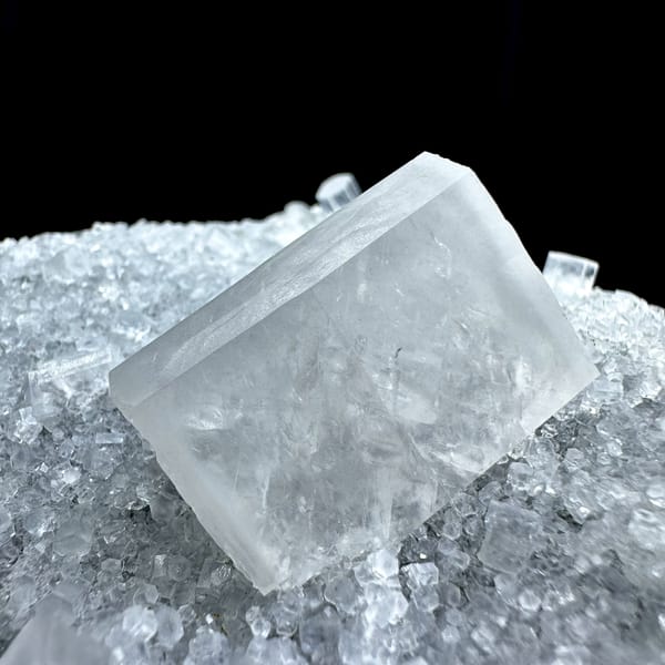 Transparent calcite prism on grey quartz druse from Fujian, China, close-up of the crystal faces