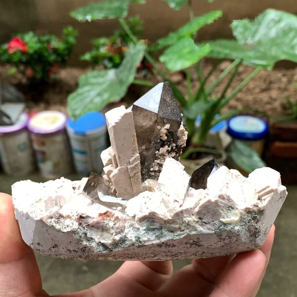 Tall smoky quartz crystal in white feldspar from Fujian, China, held in hand