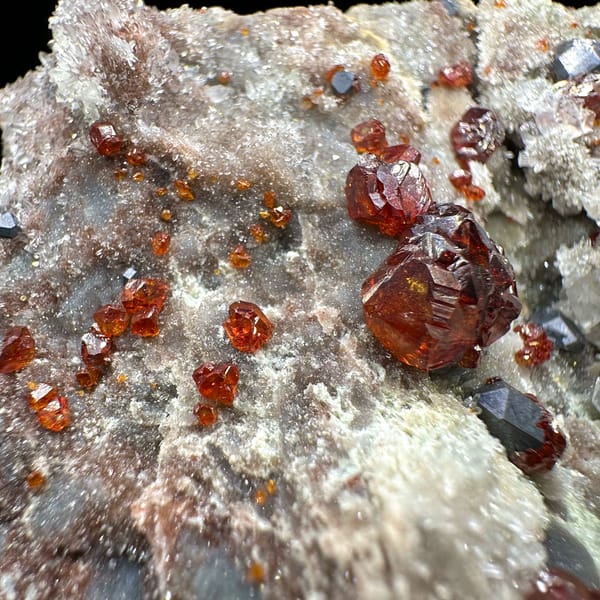 Red gem sphalerite crystals with galena on white quartz-calcite plate from Hunan, China, close-up of the crystal faces