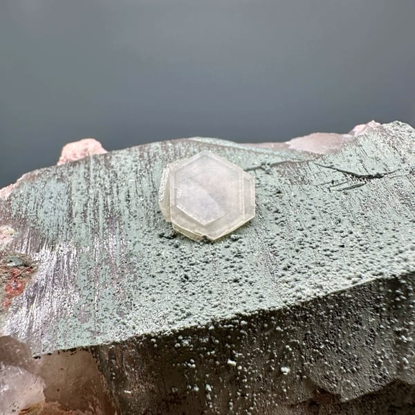 Grey hexagonal calcite plate with small white crystal and smoky quartz from Yunxiao, Fujian, close-up of the crystal faces