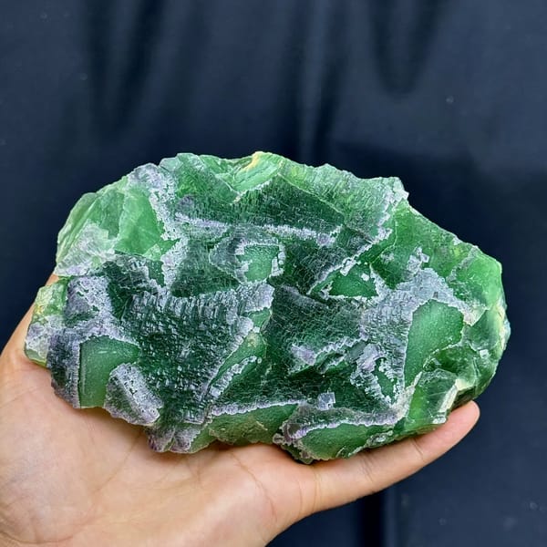 Slab of deep emerald-green stepped fluorite from Zhejiang, China, held in hand