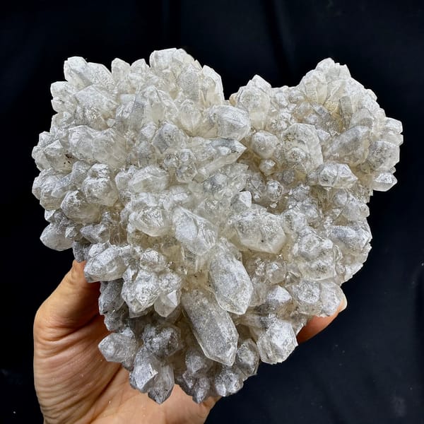 Heart-shaped cluster of pale quartz points from Inner Mongolia, China, held in hand