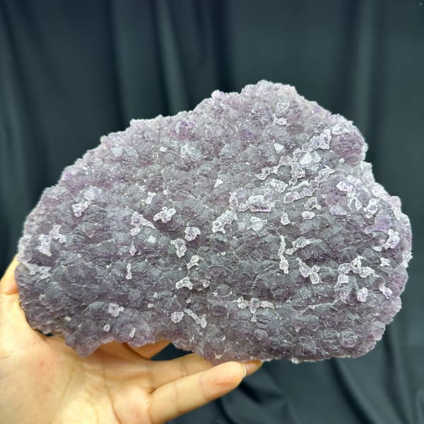 Translucent purple and green fluorite slab from Fujian, China, front view in daylight, held in hand