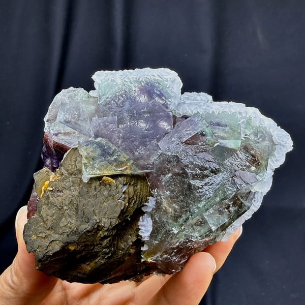 Pale purple phantom fluorite with pyrrhotite and calcite from Inner Mongolia, China, held in hand