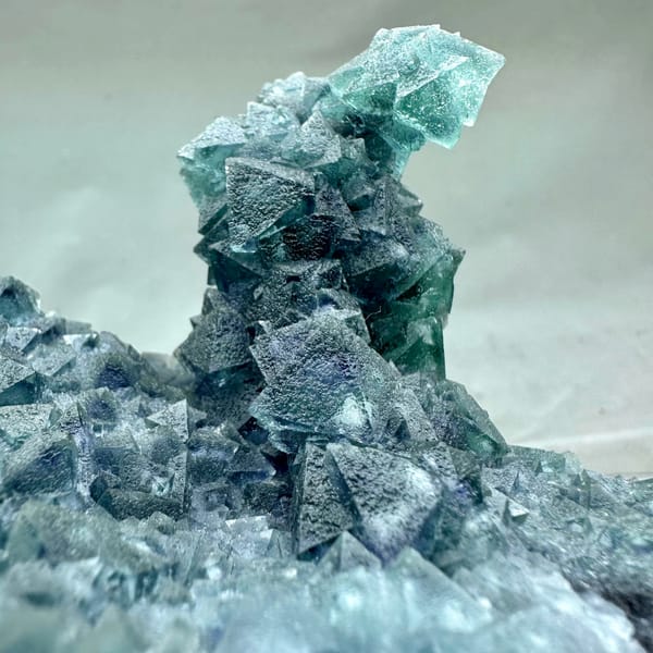 Teal-green octahedral fluorite tower on dark quartz plate from Inner Mongolia, China, close-up of the crystal faces