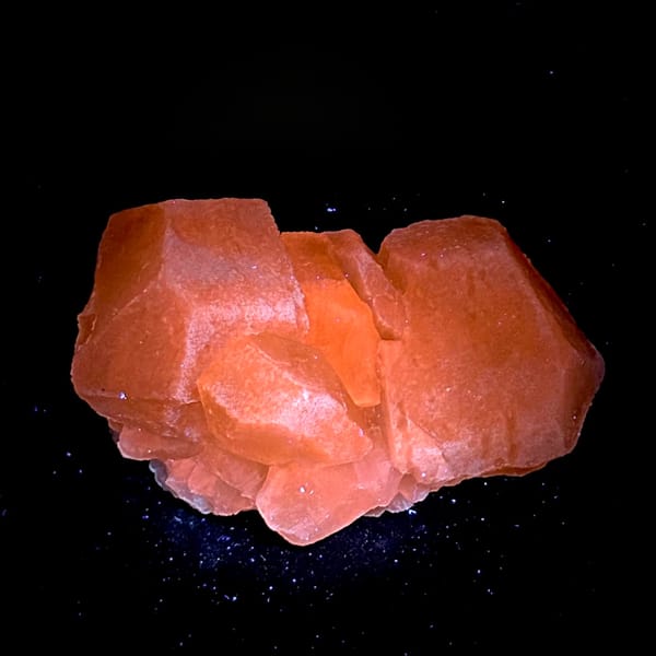 Calcite cluster fluorescing salmon-red under UV, from Hunan, China