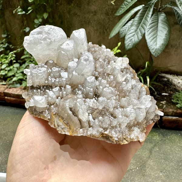 Pale plate of stubby prismatic calcite crystals from Guangxi, China, detail of the matrix contact