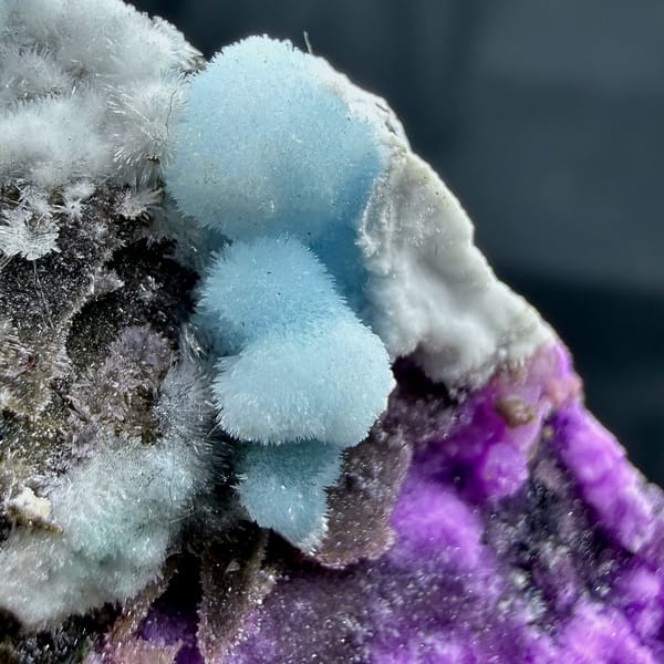 Magenta, blue and white aragonite on dark rock wedge from Yunnan, China, second angle