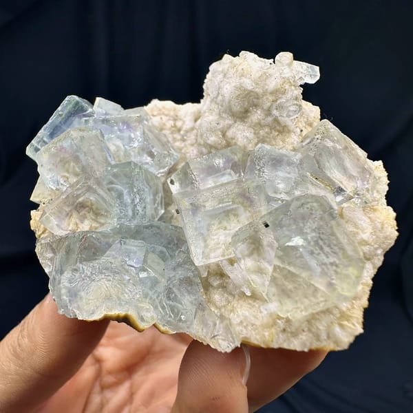 Purple-blue fluorite cubes with calcite, from Shangbao Mine, Hunan, China, front view in daylight, held in hand