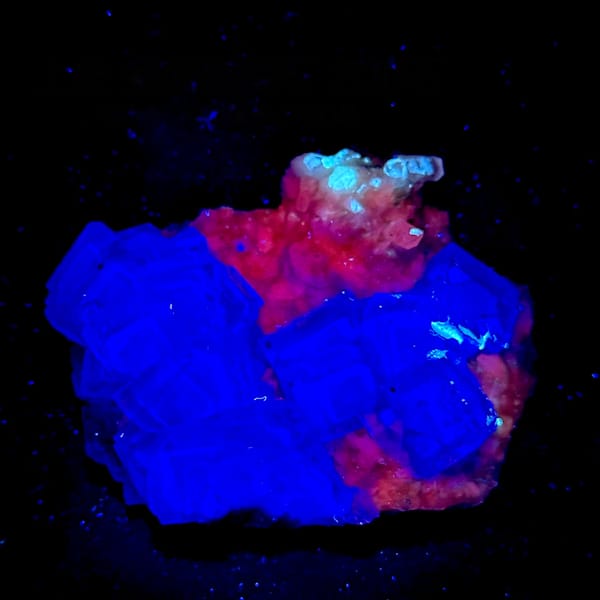 Purple-blue fluorite cubes with calcite under UV light, from Shangbao Mine, Hunan, China