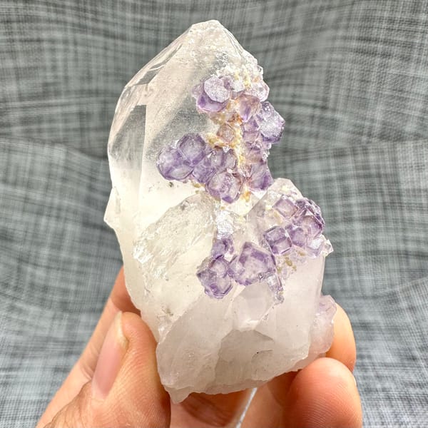 Clear quartz crystal with chain of purple fluorite cubes from Yaogangxian Mine, Hunan, China, detail of the matrix contact