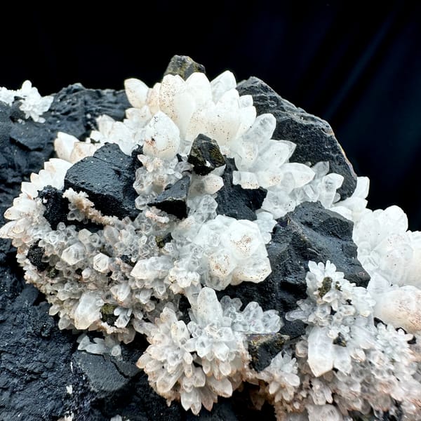 Pale red quartz crystals on black matrix with chalcopyrite from Jiangxi, China, close-up of the crystal faces