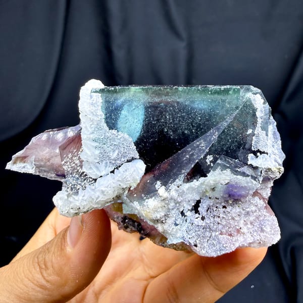 Phantom purple fluorite glowing when, from Inner Mongolia, China, front view in daylight, held in hand