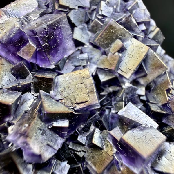 Plate of iridescent purple fluorite cubes with rainbow sheen from Inner Mongolia, China, close-up of the crystal faces