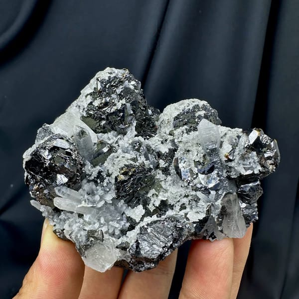 Black botryoidal marmatite with clear quartz needles from Inner Mongolia, China, held in hand