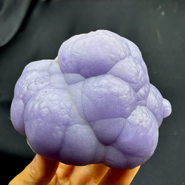 Lavender botryoidal agate mass with purple fluorite from Henan, China, held in hand