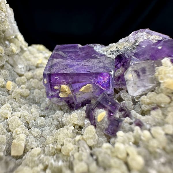 Deep purple fluorite cubes on tan quartz and mica from Yaogangxian Mine, Hunan, China, close-up of the crystal faces