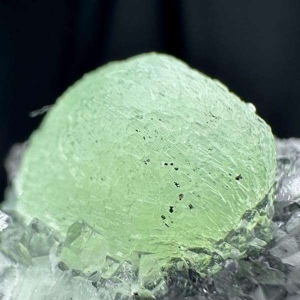 Pale green prehnite ball on dark quartz druse from Sichuan, China, reverse side