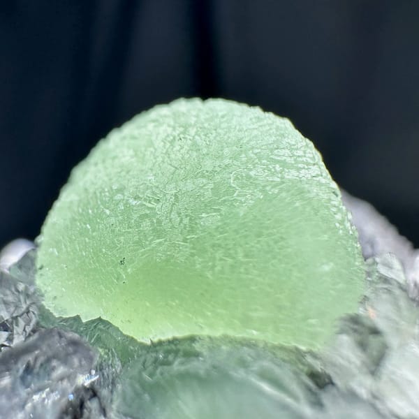 Pale green prehnite ball on dark quartz druse from Sichuan, China, top view