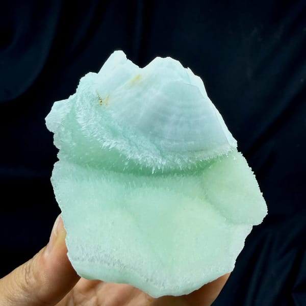 Smooth aqua-green acicular aragonite plate from Yunnan, China, held in hand