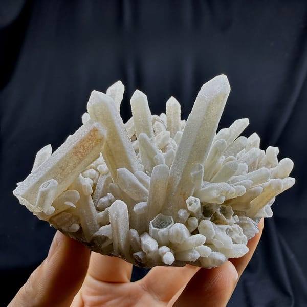 Sugar-textured pale quartz needles in spiky cluster from Guangdong, China, held in hand