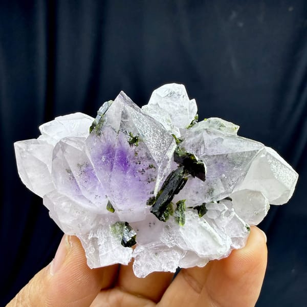 Pale lilac garden-quartz rosette with dark green epidote from Sichuan, China, held in hand
