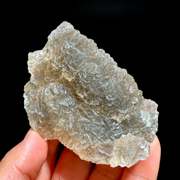 Grey-green fluorite mass sprinkled with pyrite from Xianghualing, Hunan, China, held in hand