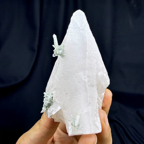 Calcite crystal with green phantom quartz, from Guangdong, China, front view in daylight, held in hand