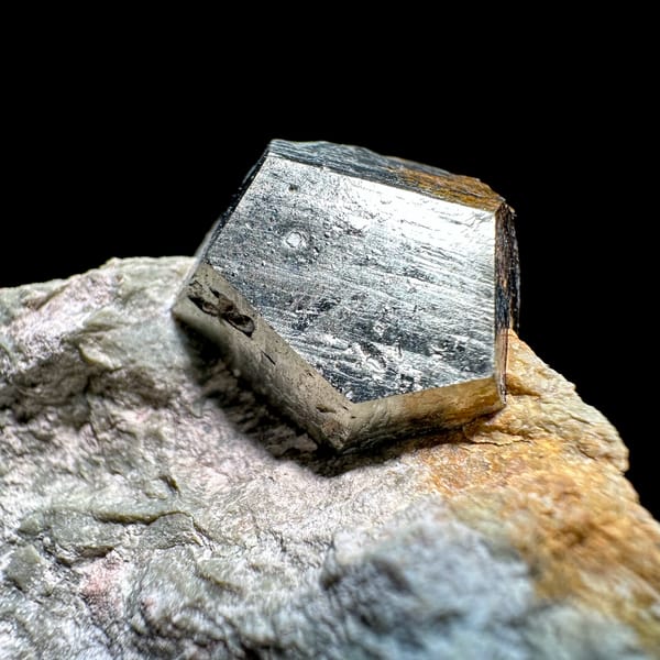 Single pyritohedral pyrite crystal on grey rock slab from Guangxi, China, close-up of the crystal faces