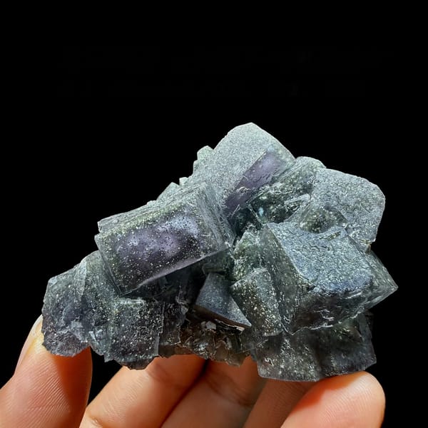 Blue-green daylight fluorite cubes enclosing pyrite from Nigeria, held in hand
