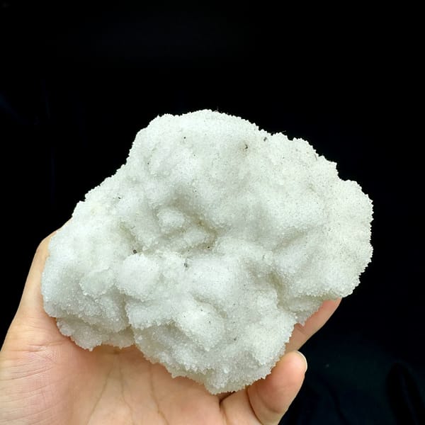 Hollow-shell quartz mass of sparkling white druse from Fujian, China, held in hand
