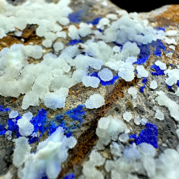 White aragonite balls with royal-blue azurite vein on rusty rock from Yunnan, China, close-up of the crystal faces