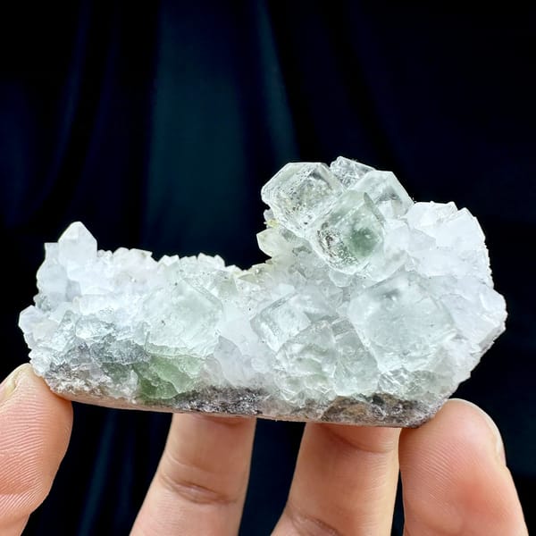 Pale green fluorite cubes with inclusions on white quartz from Guangdong, China, held in hand