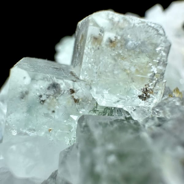 Pale green fluorite cubes with inclusions on white quartz from Guangdong, China, close-up of the crystal faces