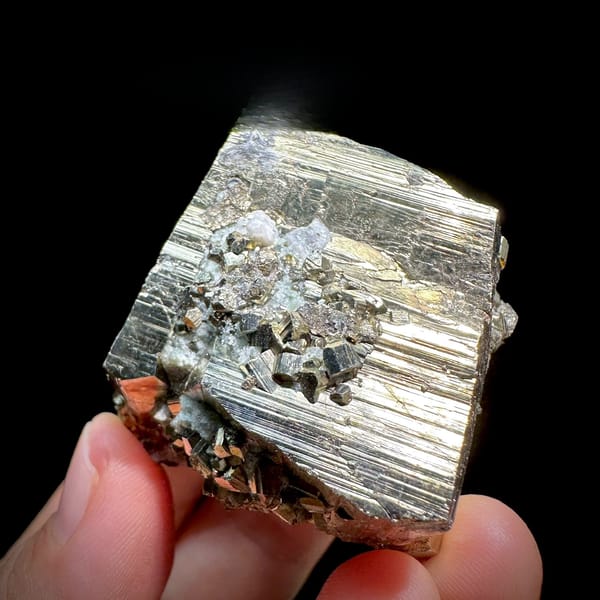 Striated pyrite cube floater with mirror faces from Hunan, China, held in hand