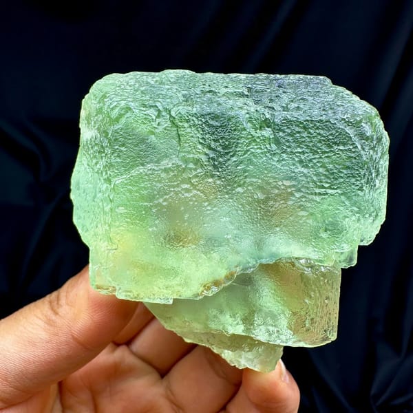 Single large translucent green fluorite cube from Fujian, China, held in hand