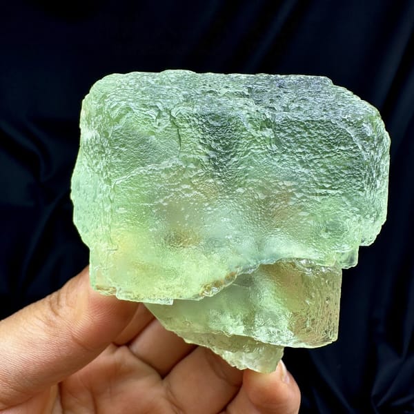 Single large translucent green fluorite cube from Fujian, China, detail of the matrix contact