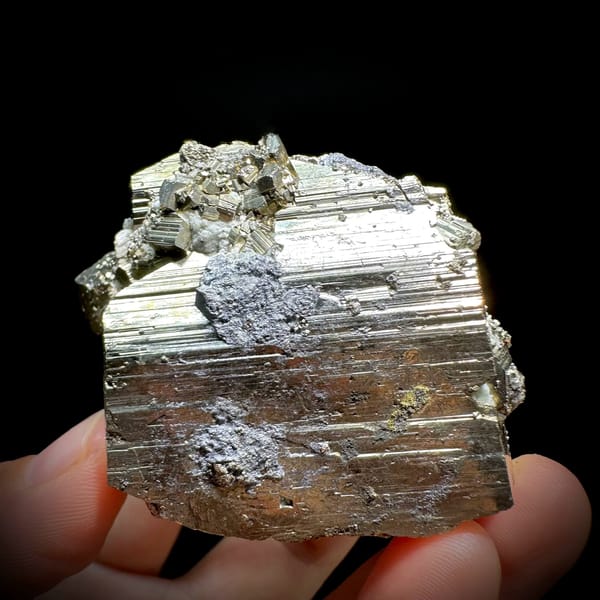Heavy striated pyrite floater with satin gold lustre from Hunan, China, held in hand